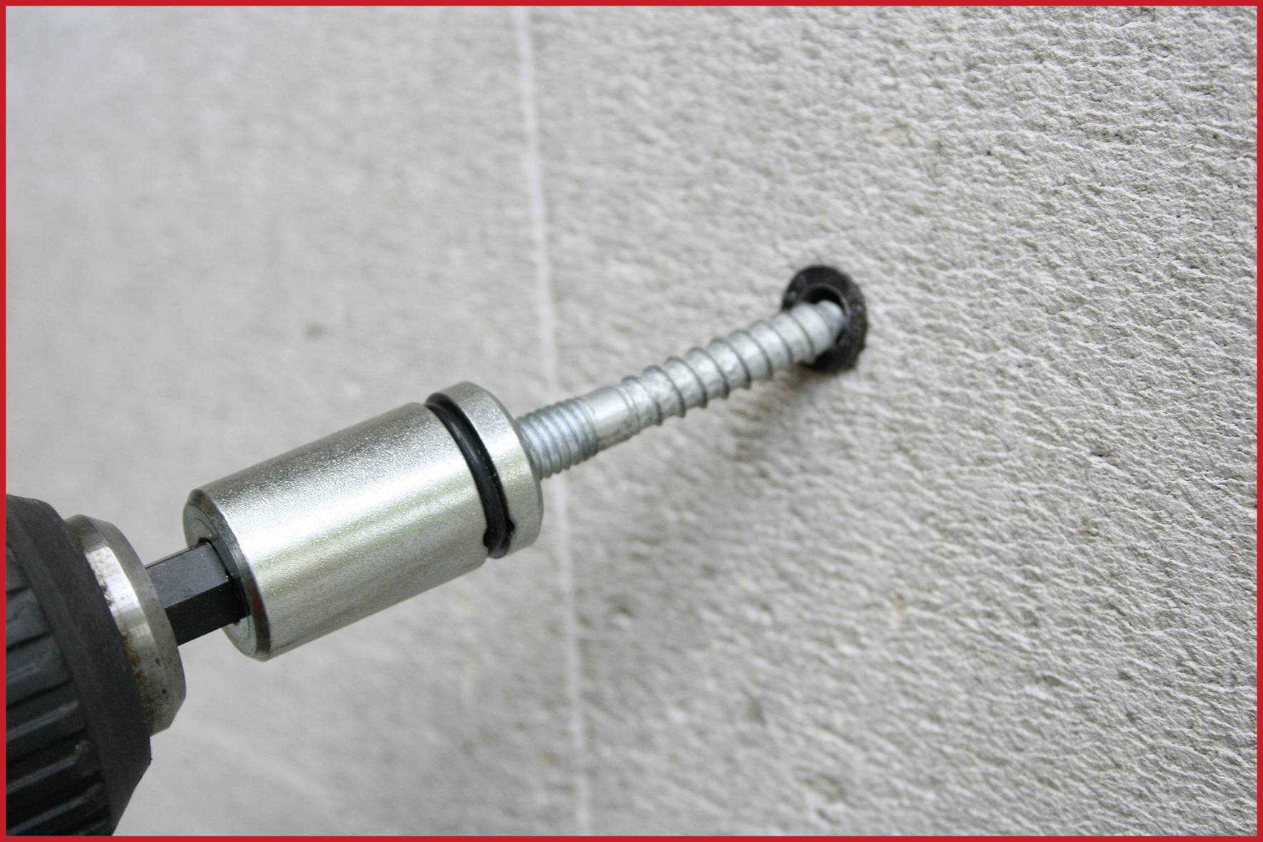 'Cordless drill drives long screw into concrete wall.'