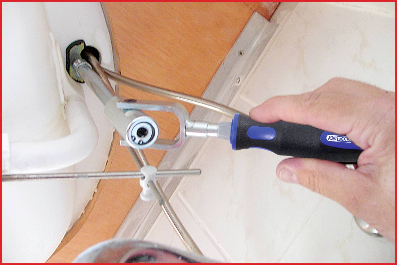 A person is installing or repairing a metal connection underneath a sink with a blue and black tool.