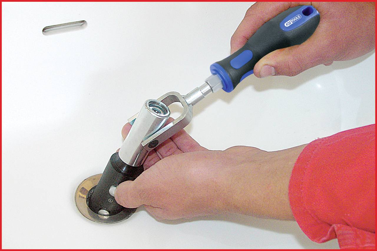 A person is repairing a drain with a tool in a bathroom.