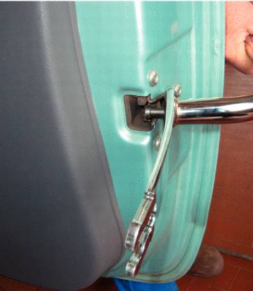 A person is pulling a protruding pin from the car door's anchoring point using a tool.