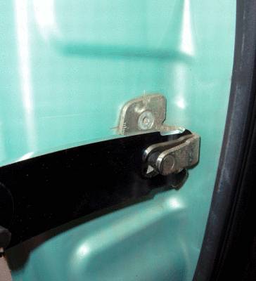 A metal fastener on a door-like structure, providing sturdy support. Light green surface in the background.