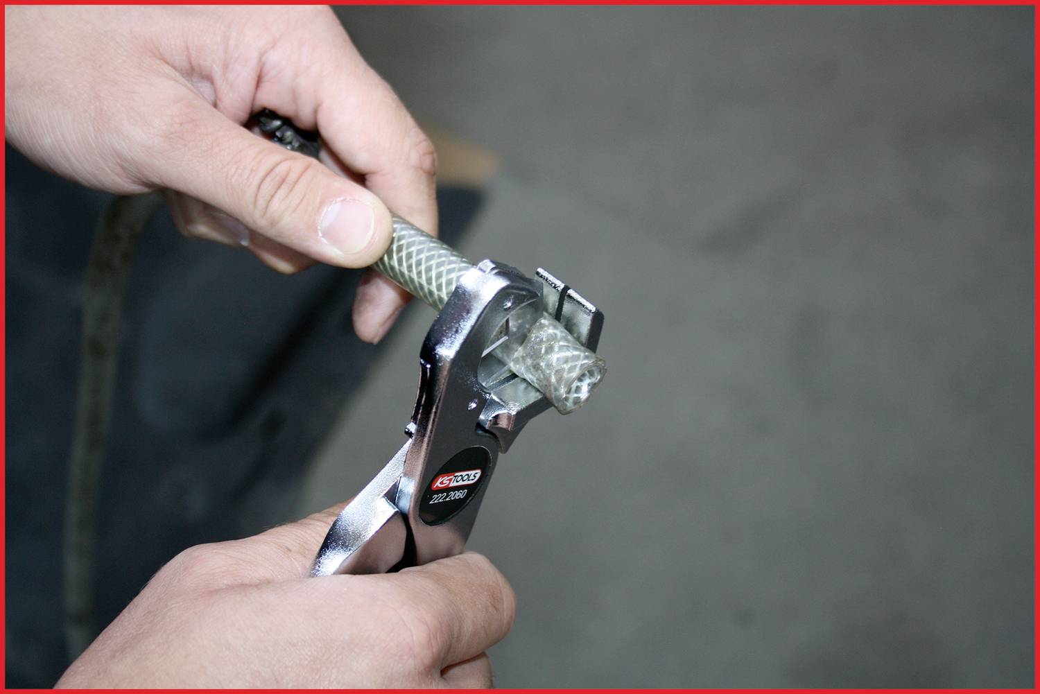 A person is cutting a braided cable with a metal tool. Hands in the foreground focus on the precise cut.