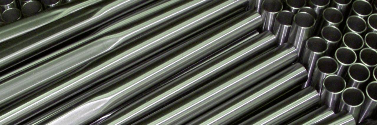 Steel metal pipes are stacked side by side. They display smooth, reflective surfaces with circular openings.