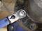 A blue torque wrench is tightening a screw on a metal flange.