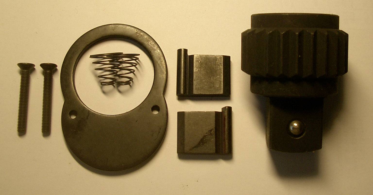 A dismantled ratchet mechanism set with screws, a spring, a metal ring, and gears on a white background.