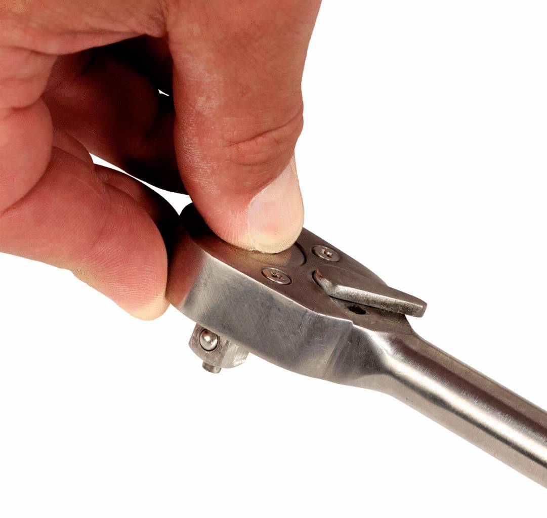 A hand holds a ratchet spanner and adjusts the direction lever.