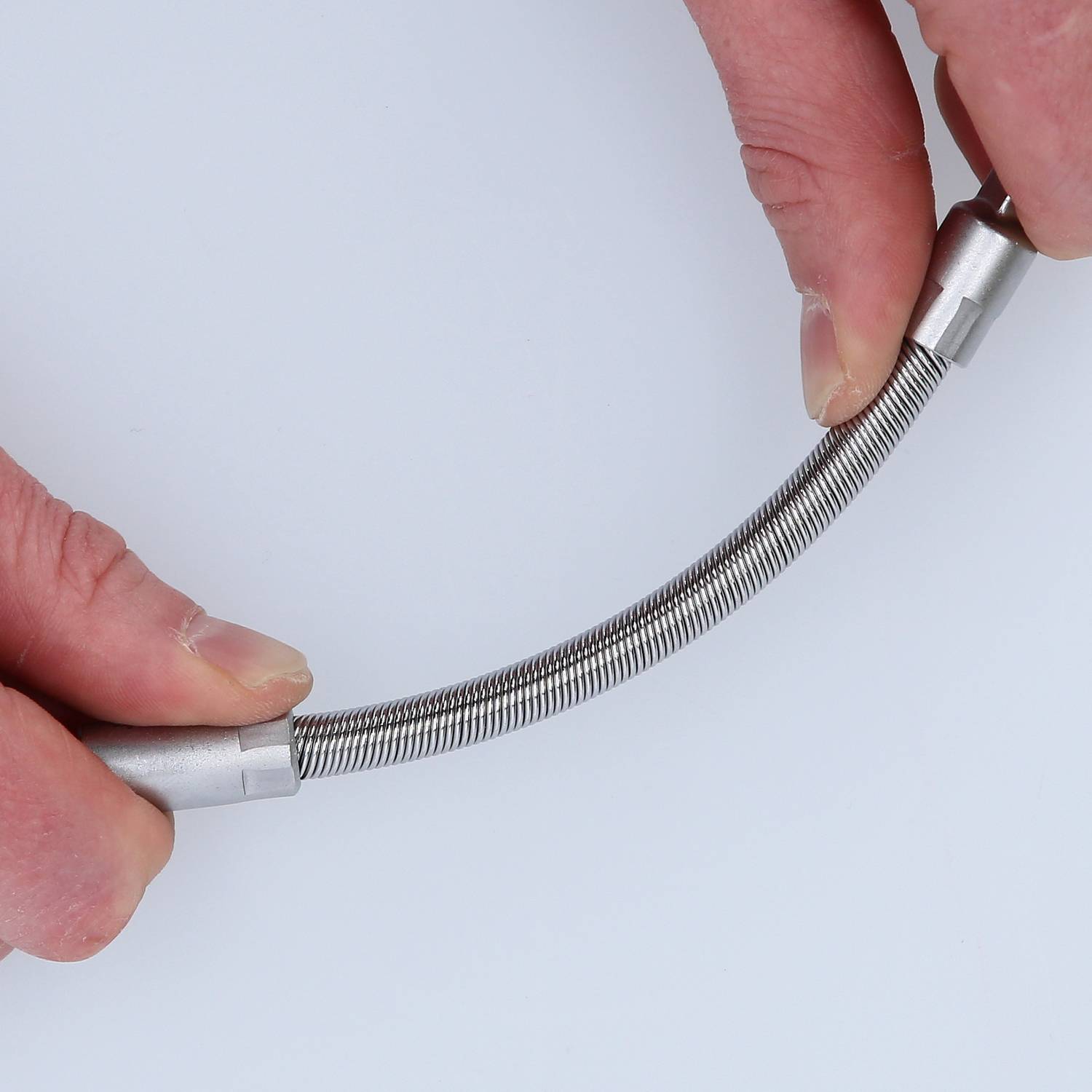 Two hands are holding a flexible metal hose. The hose is bent and appears to be stretchable.