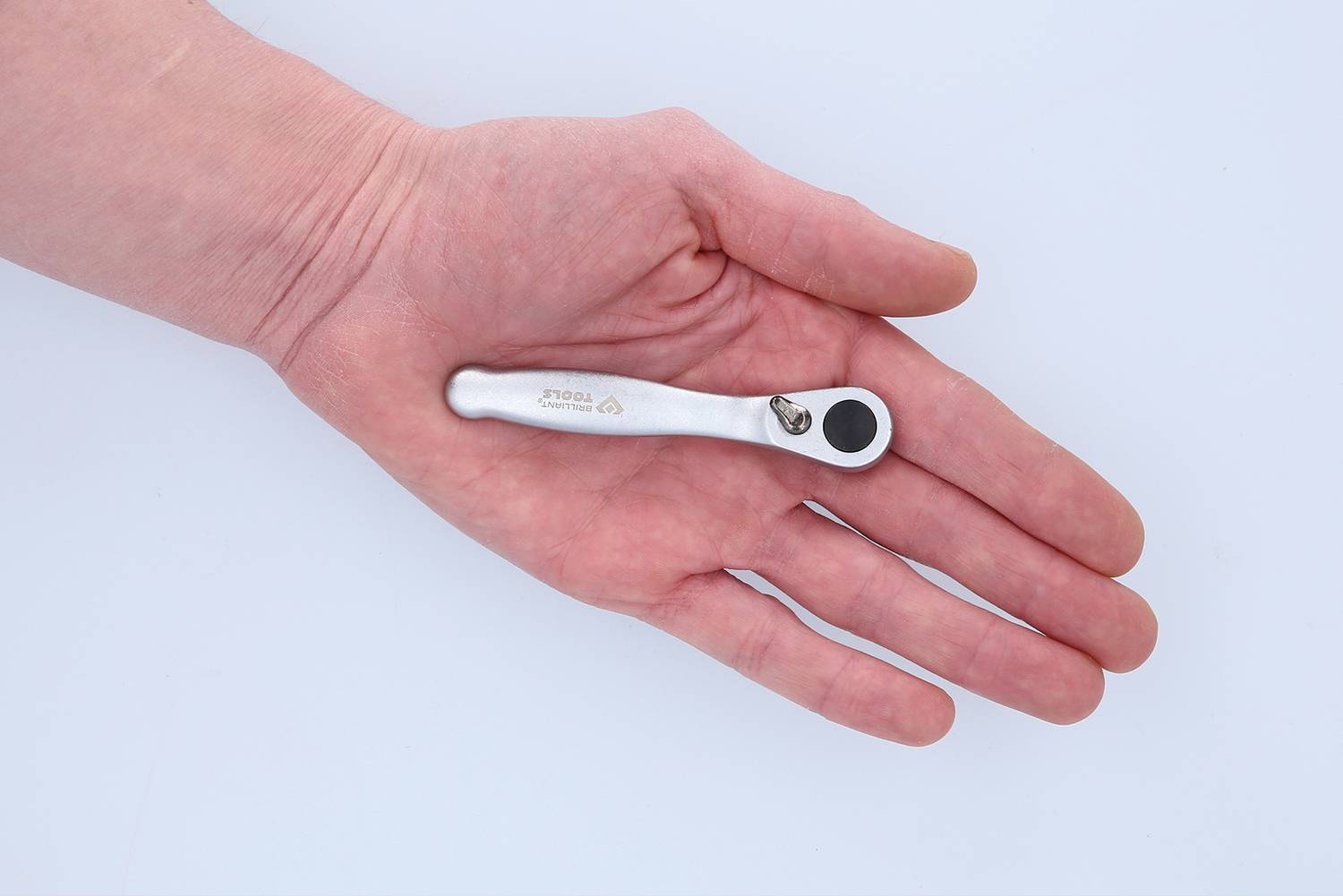 A hand is holding a small ratchet spanner.