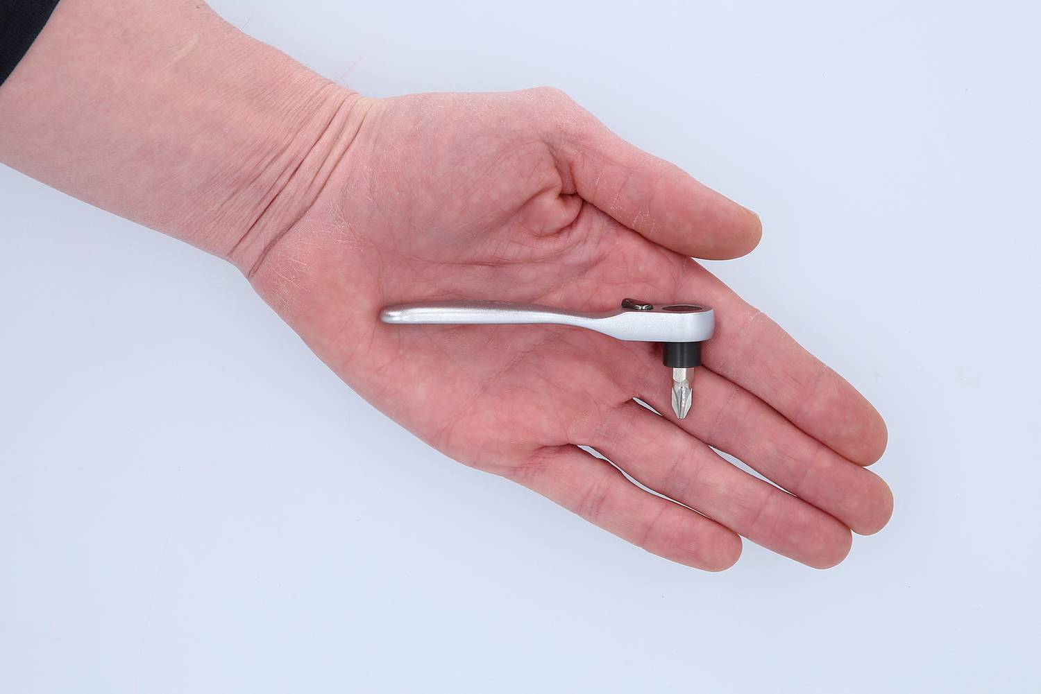 A hand is holding a small ratchet screwdriver with a mounted screwdriver bit, against a white background.