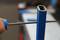 A file is pulled through a blue metal tube to smooth the inner edges. Some blurry tools are in the background.