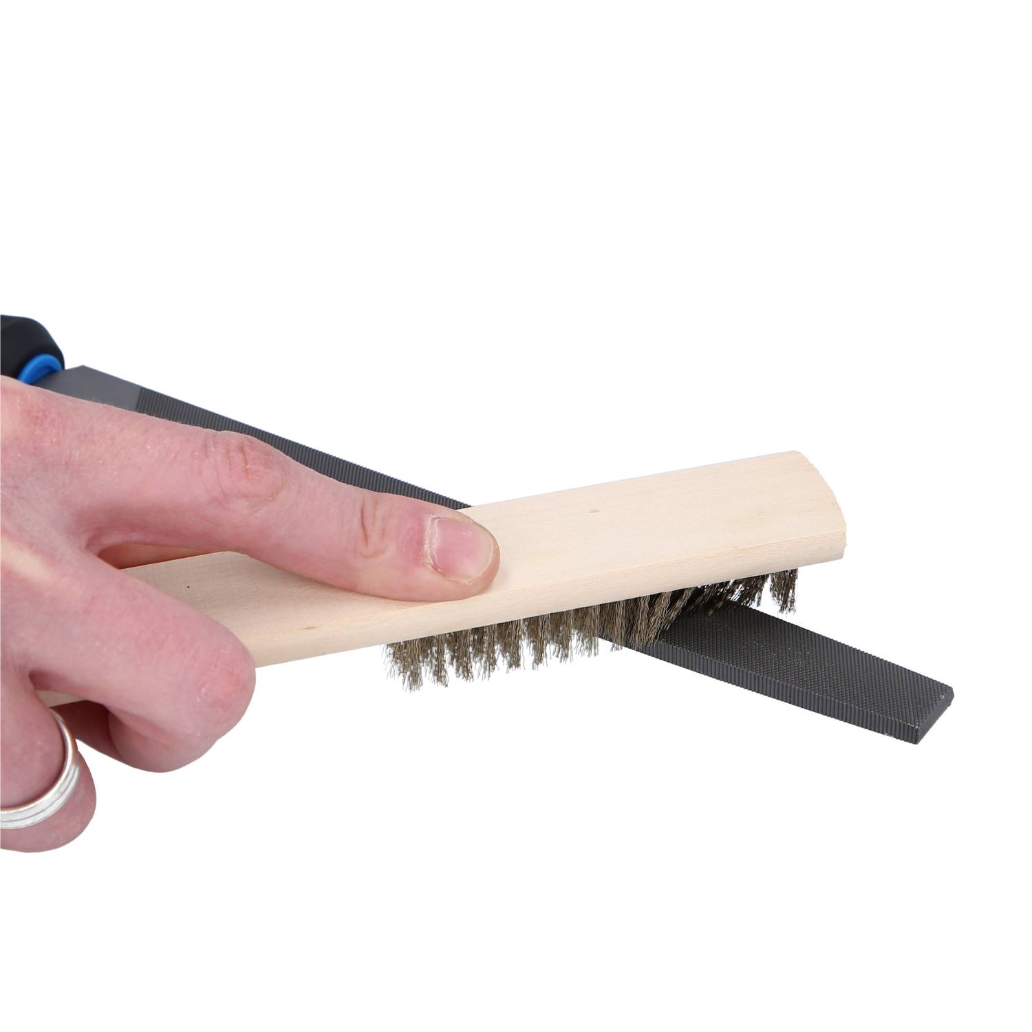 A hand holds a wire brush and cleans an arrow.