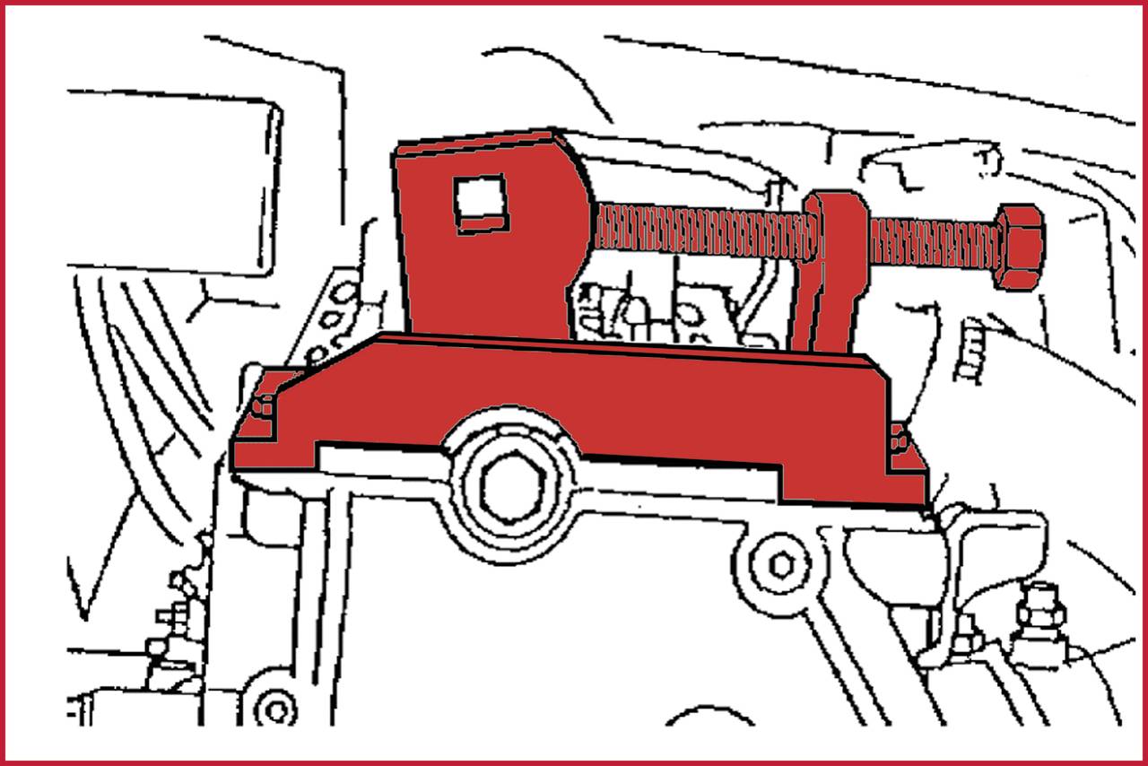 A red mechanical device with a screw mechanism is mounted on an engine block, possibly a tool for clamping or fixing.