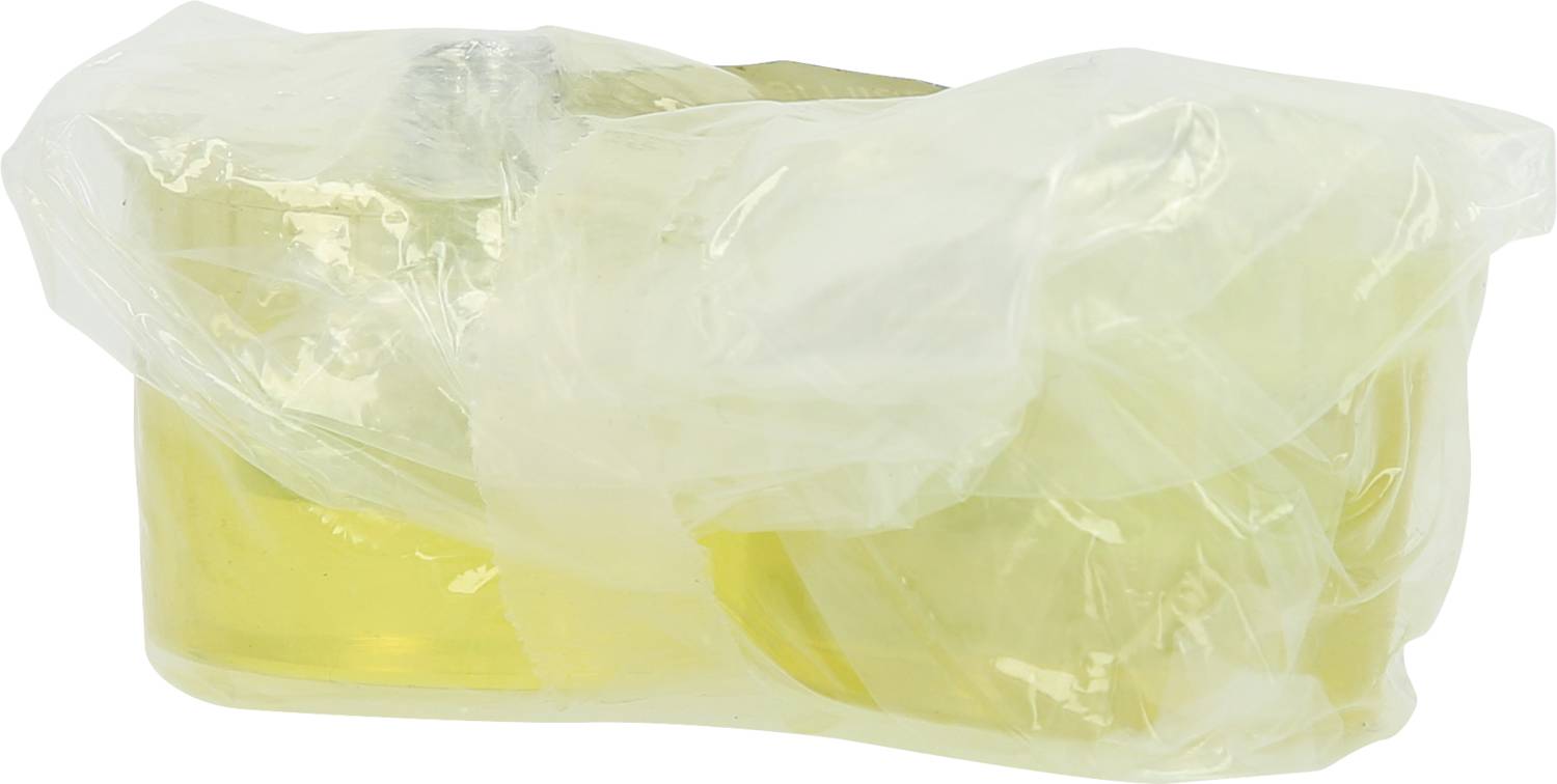 A yellow block wrapped in plastic film, possibly a piece of soap or cheese, is lying on a white surface.