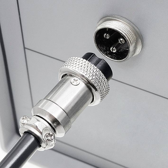 A metallic circular pin connector and a matching three-pin socket on a device, ready to be connected.