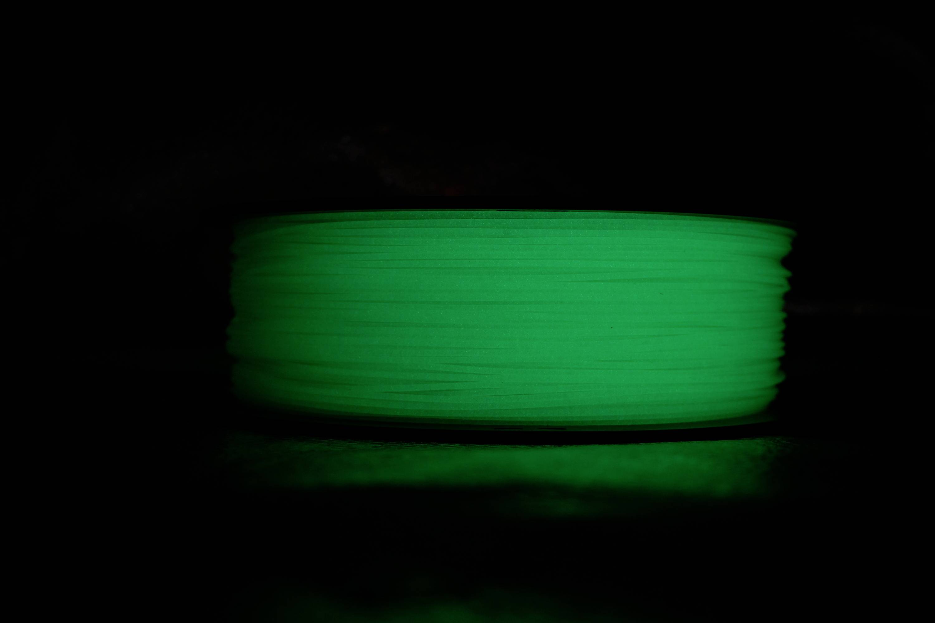 A reel of luminous, green filament on a dark background.