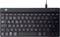 A black, compact QWERTY keyboard with a function key row, arrow keys, and attached USB cable, viewed from above.