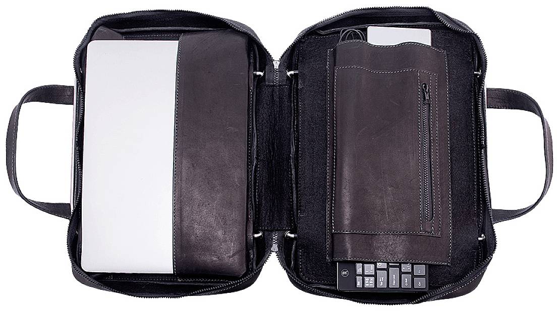 Open leather bag with laptop, notebook, and keyboard.