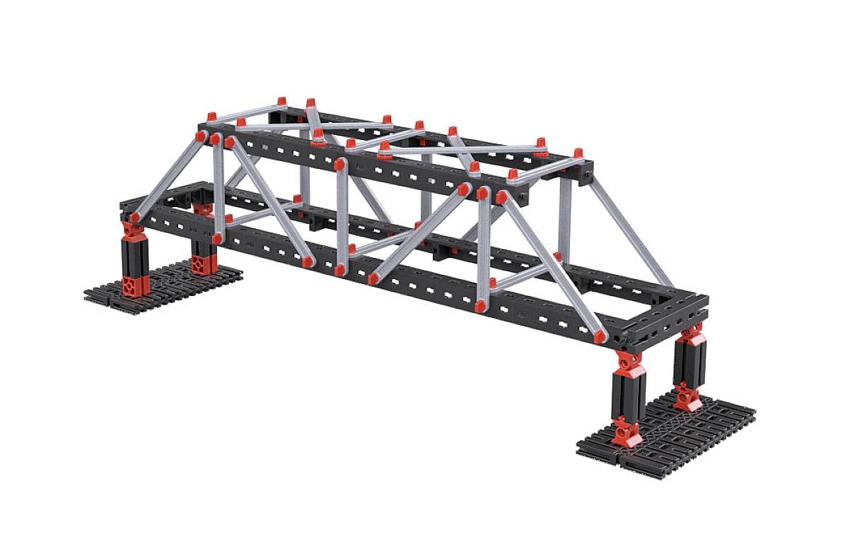 'A model of a truss bridge made from black and grey bars with red connecting elements, supported on pillars.'