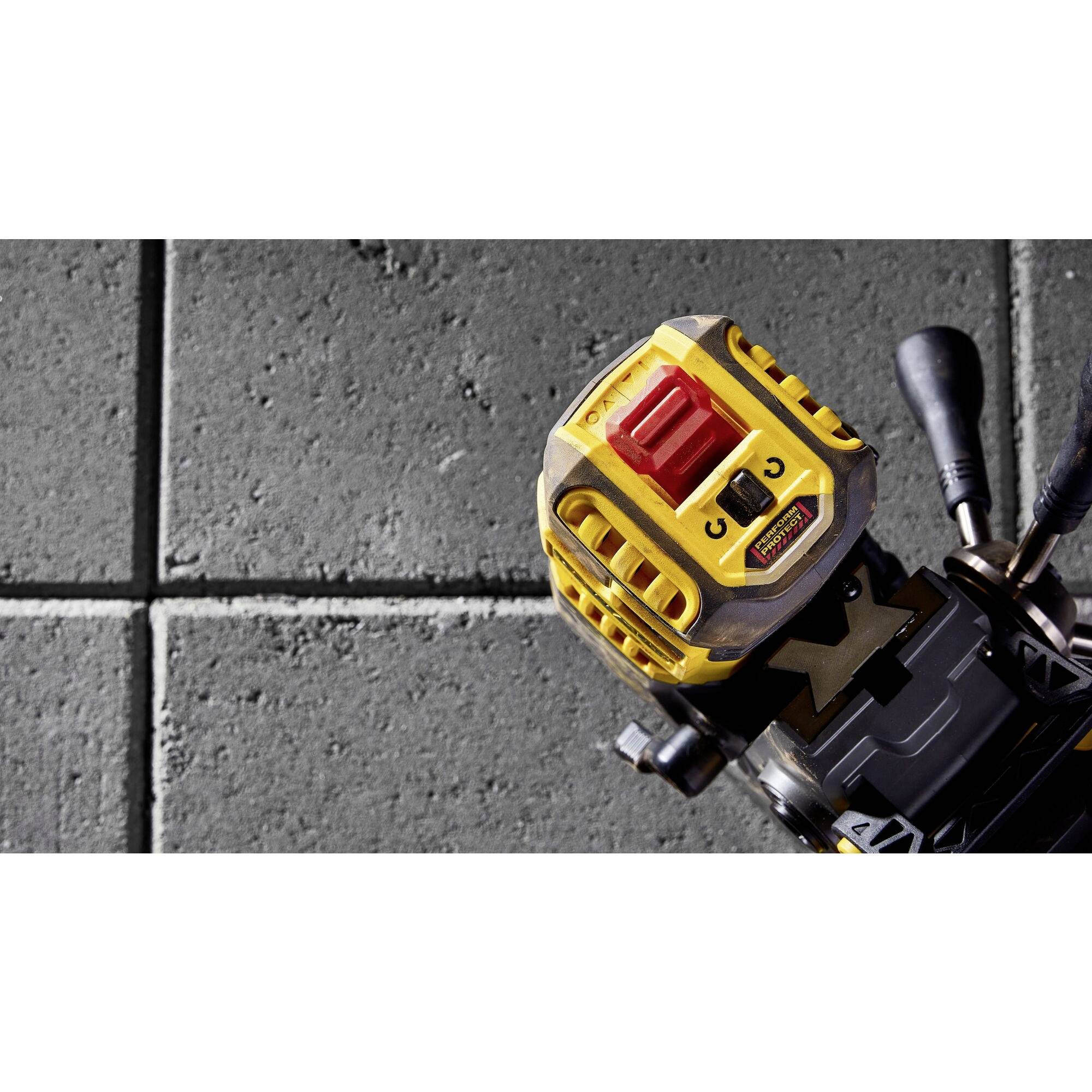 Close-up of a yellow machine with switches on a grey tiled floor. The device section is not fully visible; context is unclear.