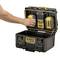 A person is placing a battery into a DeWalt ToughSystem 2.0 charging station, which is integrated into an open, black toolbox.