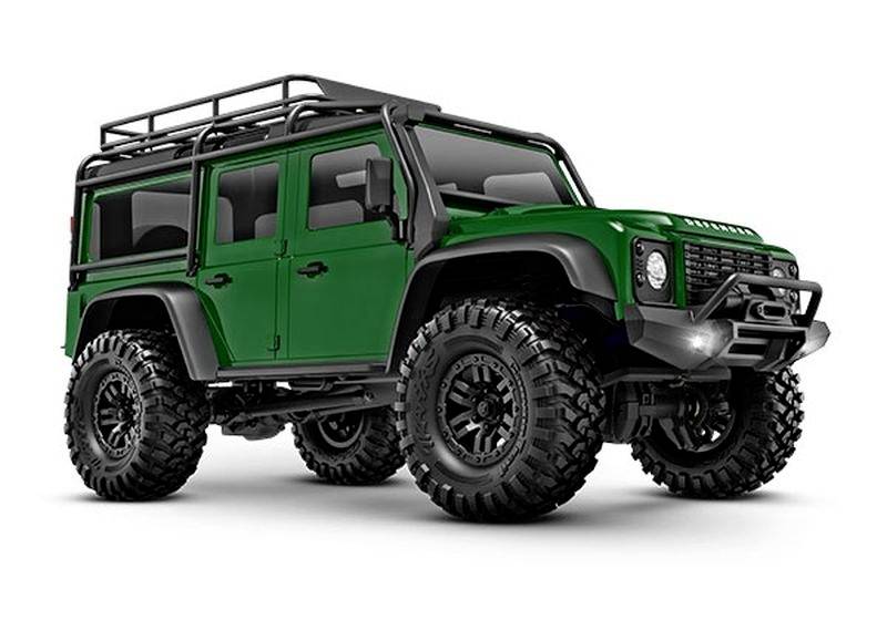 A green off-road vehicle with robust tyres and a roof rack is standing in a studio. The vehicle looks rugged and powerful.