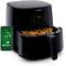 A black air fryer with digital controls and a smartphone displaying an app for controlling the air fryer.