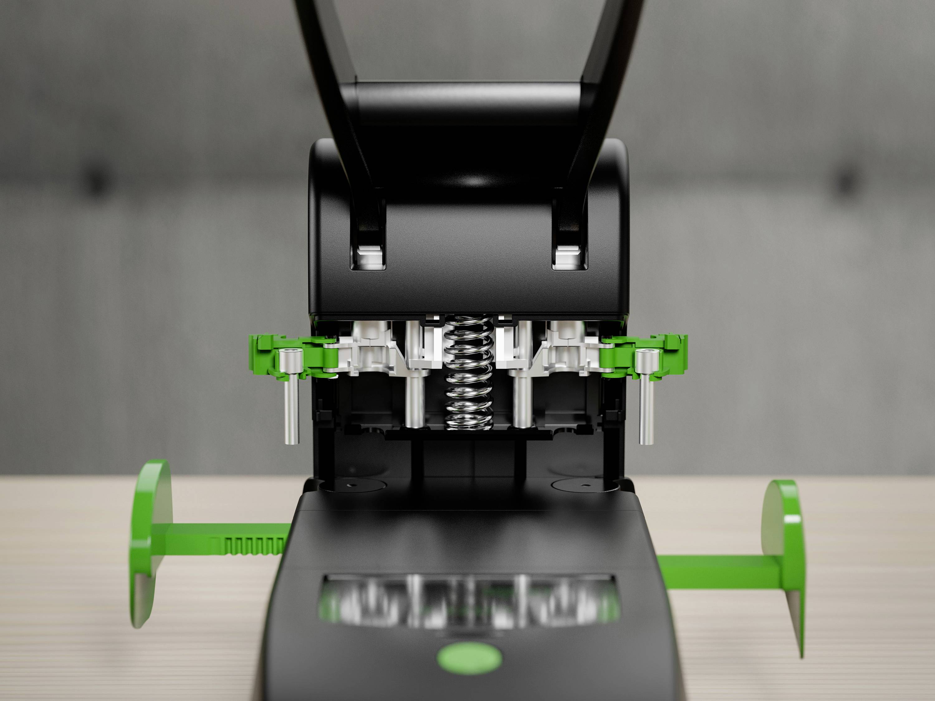 A black and green hole punch on a table, shown from a front view. The metal punches are visible.