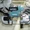 A person wearing gloves is performing a precise cut with a blue electric saw in a workshop.