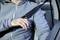 A man in a car fastens his seat belt. The focus is on the action that emphasises safety.