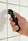 A hand holds a grout rake and removes mortar between white tiles on a wall.