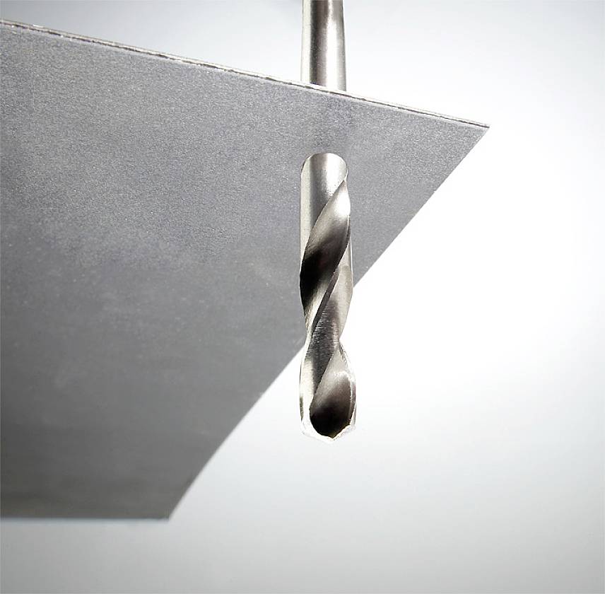 A metal drill penetrates a thin metal sheet. The image captures the precision and strength of the drill in action.