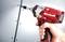 A hand holding a red cordless drill is screwing a screw into a blue surface. The drill is branded with 'Einhell'.