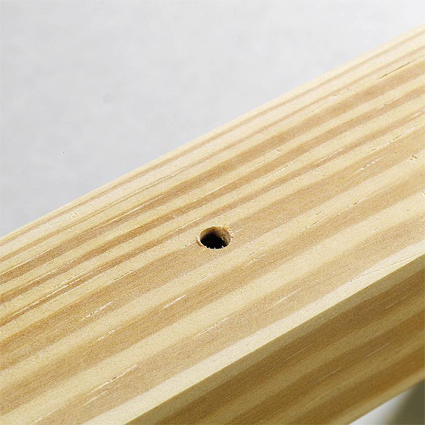 A close-up of a wooden beam with a small drill hole in the centre, on a light background.
