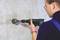 A person is drilling a hole in a wall with a power drill.