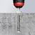 A drill with a red and black handle is drilling a hole in a concrete surface.