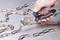 A hand is holding pliers about to cut through a metal chain on a table.