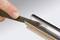 A hand is filing a metal edge. The photo demonstrates the use of a file to smooth or shape metal surfaces.