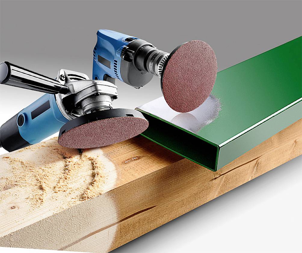 Two grinding machines with red discs are processing wood and metal. On the left, wood is being sanded, while on the right, a green metal surface is being polished.