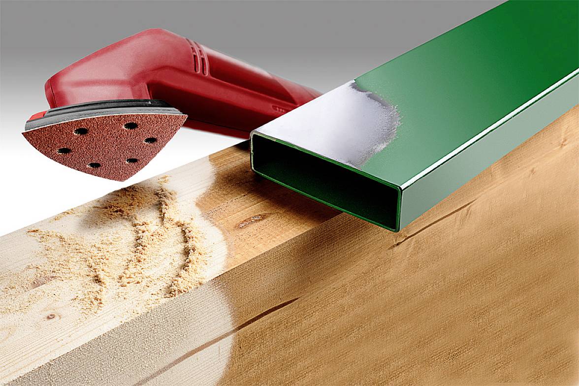 A red sanding machine grinds wood, creating a smooth surface. Beside it, a green metal pipe provides a contrast to the wood's texture.