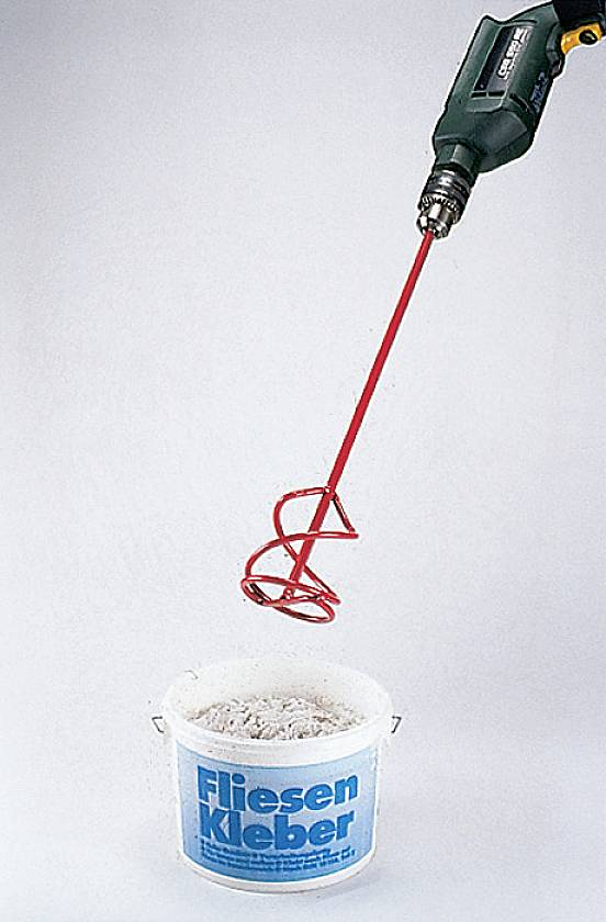 A drill mixer is preparing tile adhesive in a bucket.