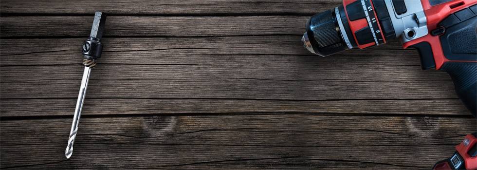 Cordless drill and drill head lie on a wooden surface. Drill head on the left, machine on the right. DIY tool.