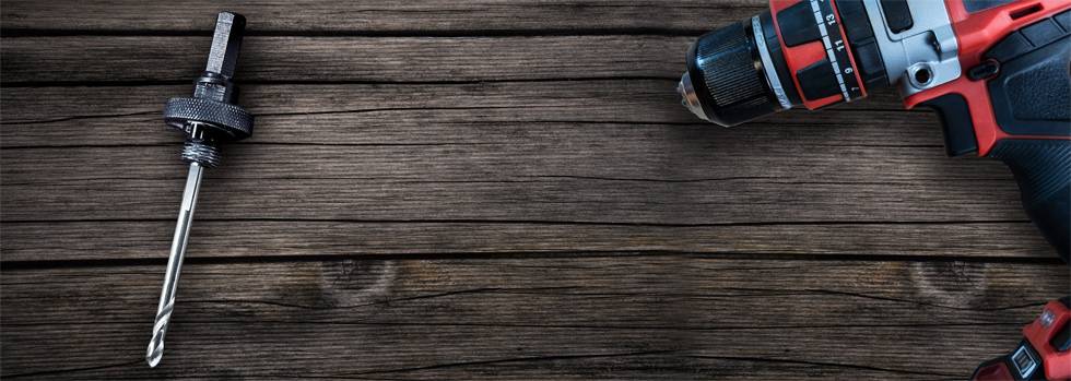 Cordless drill with drill bit on wooden background. A drill bit on the left, the drill on the right. Focus on tool equipment.