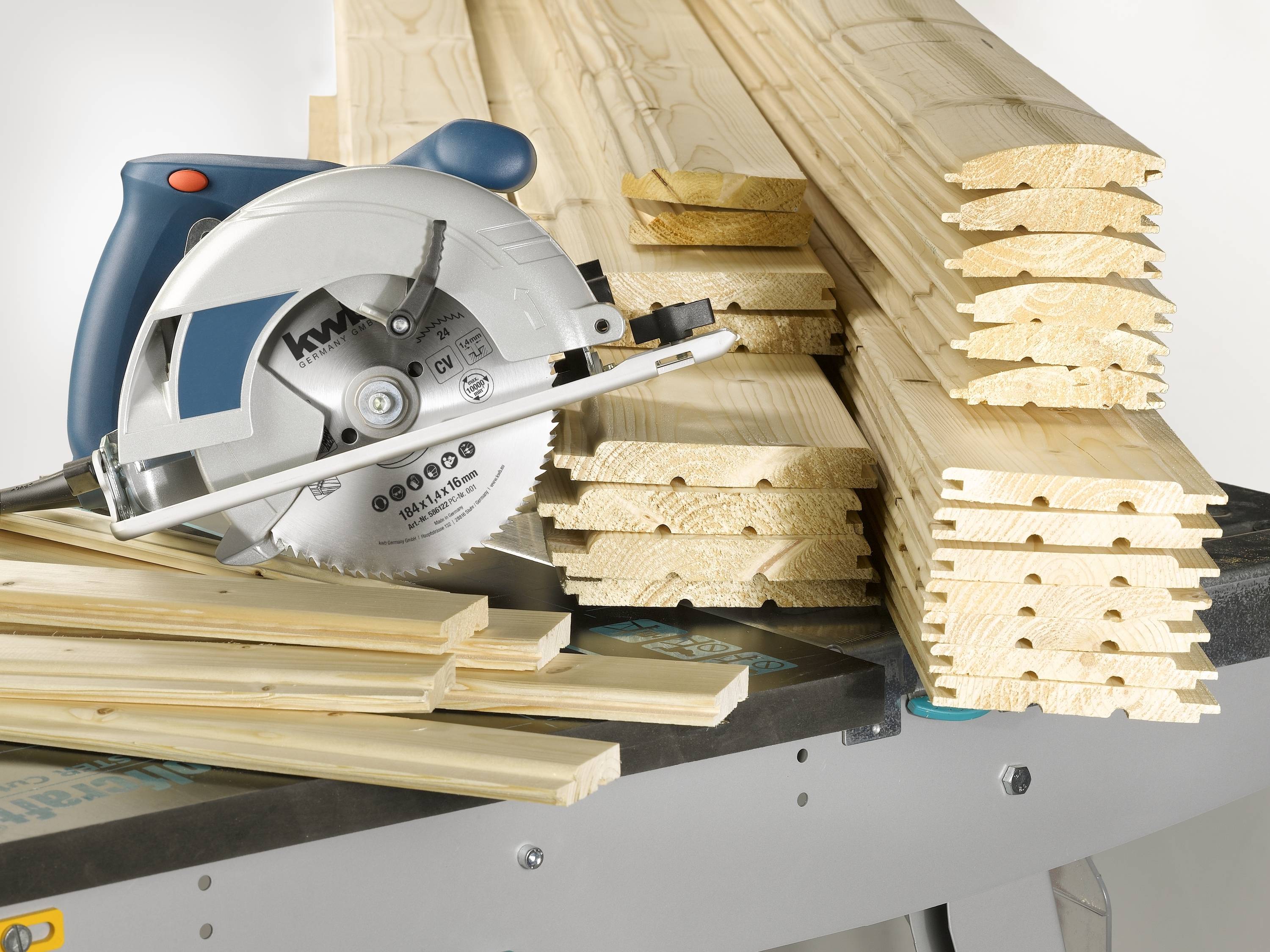 A circular saw lies beside a stack of wooden planks on a workbench, ready for woodworking.