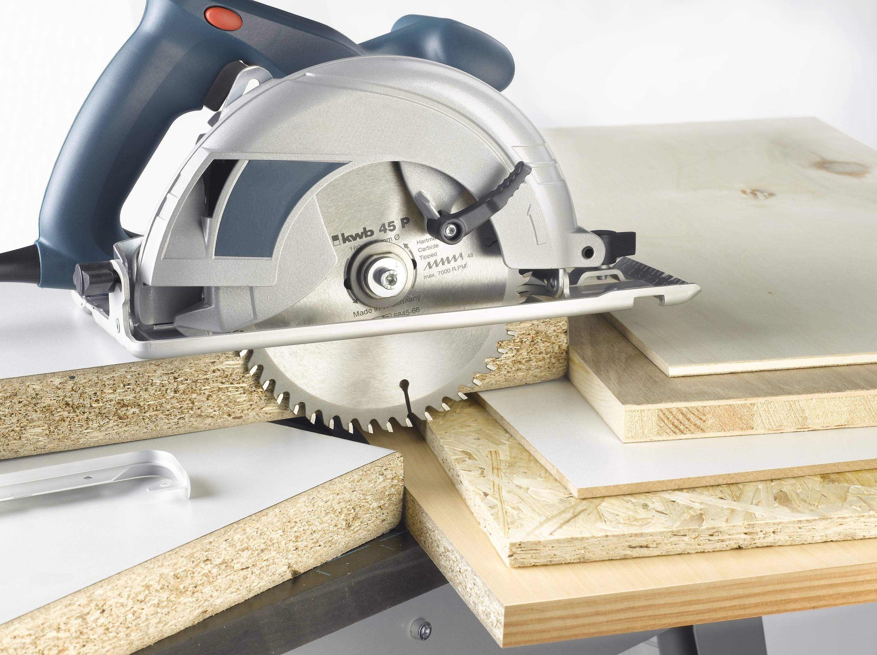 A circular saw cuts through several wooden boards. The saw is electric and manually operated. Saw blades are visible.