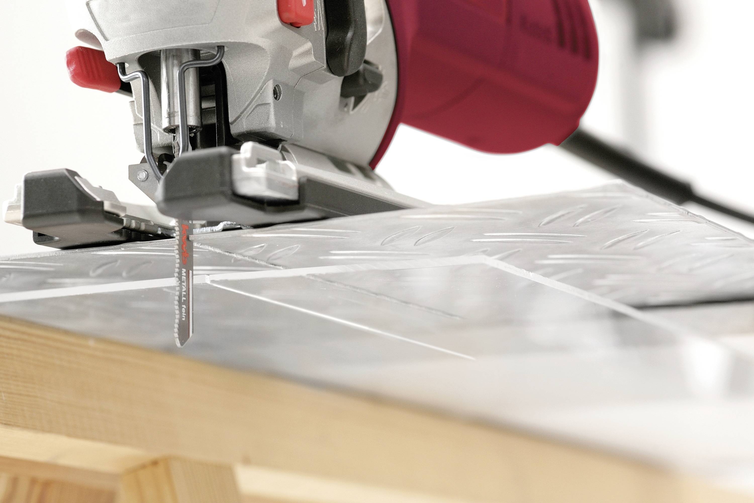 Close-up of a jigsaw cutting through a wooden board.