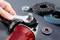 A hand is securing a disc to an angle grinder. Various grinding discs and a washer are lying in the background.