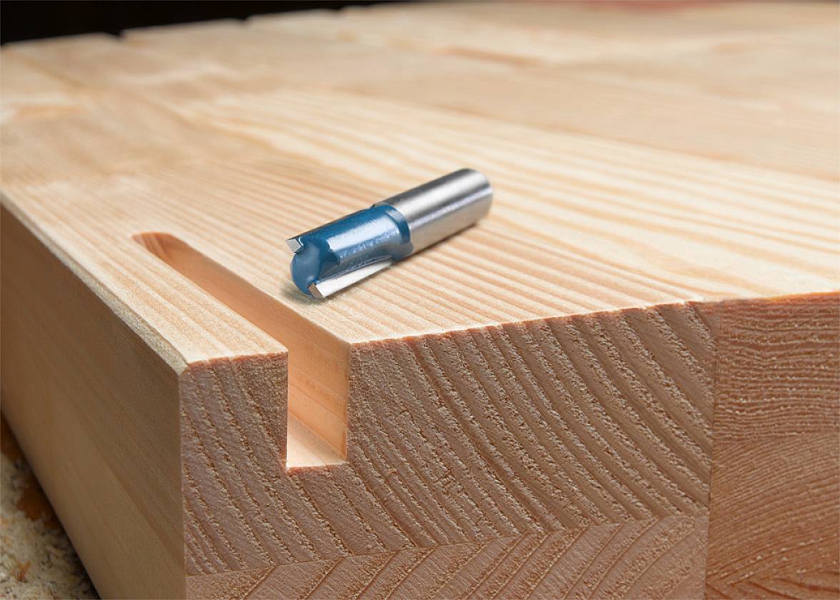 Drill rests on wooden board with narrow rectangular recess. Suitable for woodworking or carpentry tasks.