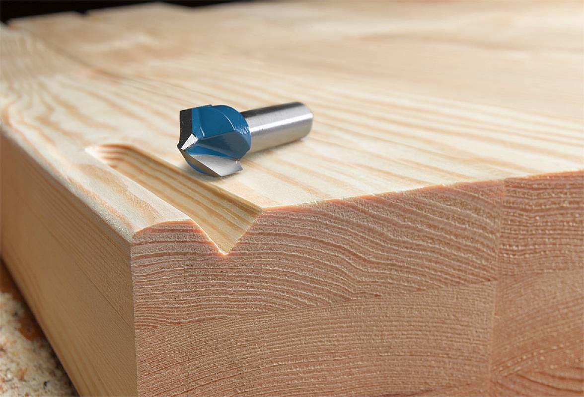 A milling cutter head rests on a solid piece of wood with a milled edge, which showcases the intricate processing and grain pattern.