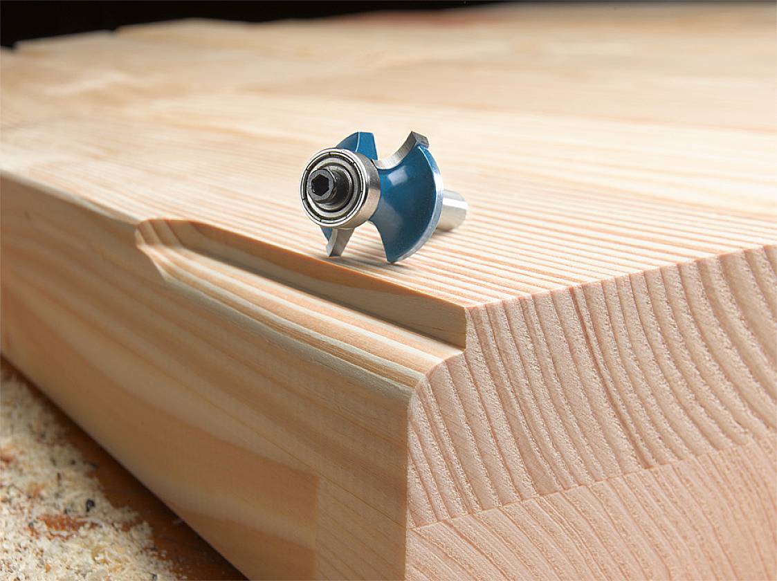 A milling cutter rests on a wooden block with a milled edge, showing smooth cuts. Indications of woodworking.