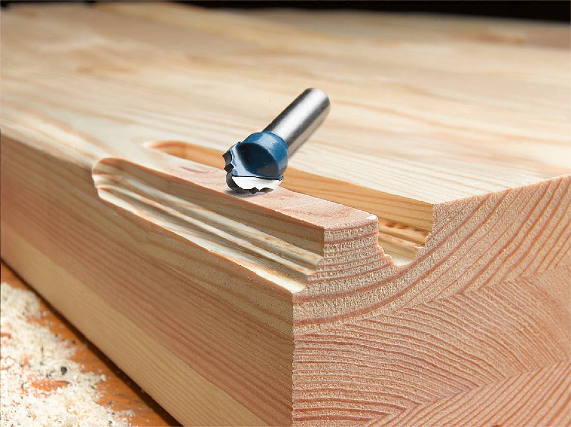 Wooden Plank with Milling Drill Bit: A milling drill bit rests on a machined groove of a solid piece of wood, surrounded by wood shavings.